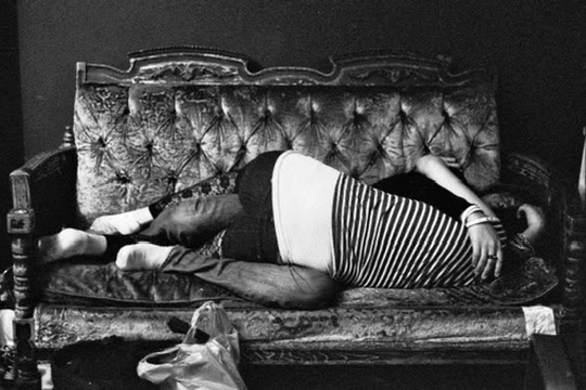 Two people asleep together on an ornate sofa in a black-and-white interior