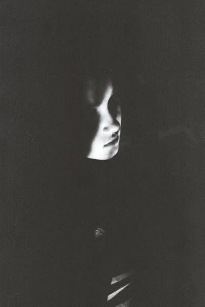 A face emerging from near-total darkness