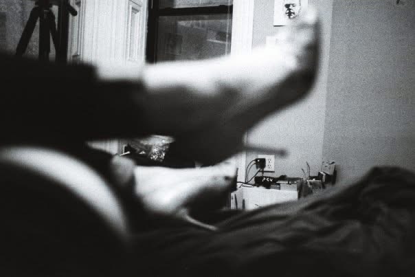 Bare feet moving above a bed in a dim interior