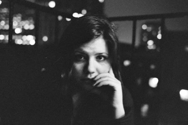 A woman looking toward the camera in a dark reflected interior