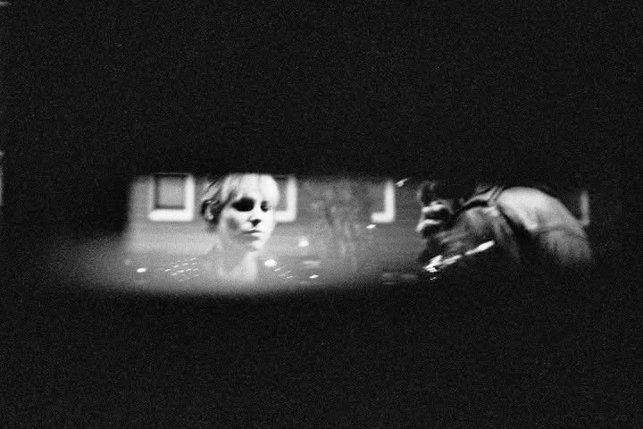 A face reflected in a rear-view mirror at night