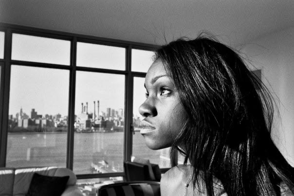 A woman in profile before a large window overlooking the New York skyline