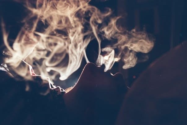 A curl of smoke lit in warm color against deep blue