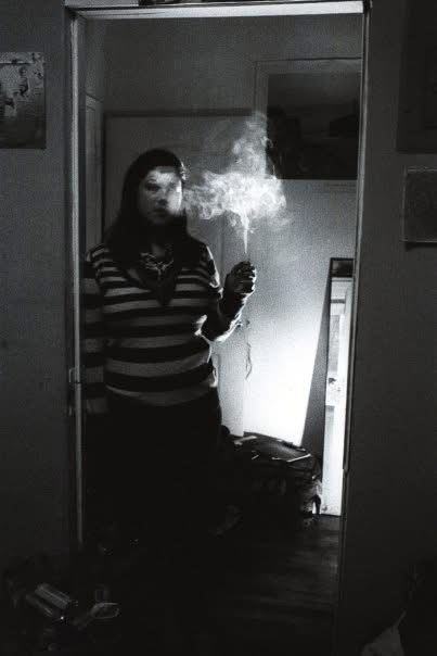 A woman holding a smoking spark in a bedroom mirror