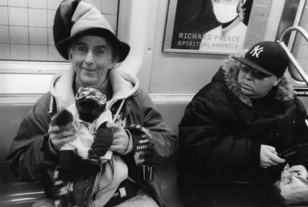 Three subway riders seated together, one holding a small dog