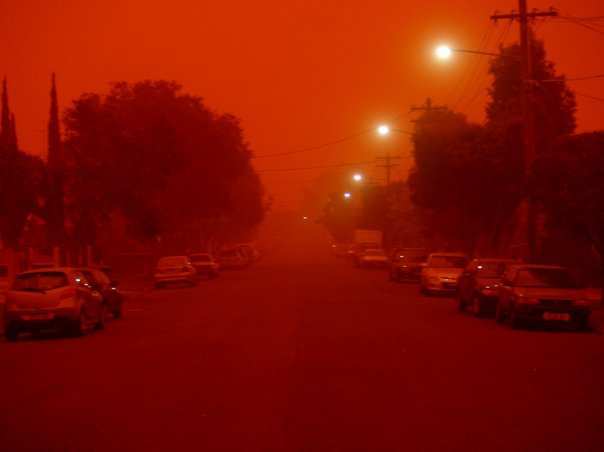 A residential street beneath a red-orange night sky