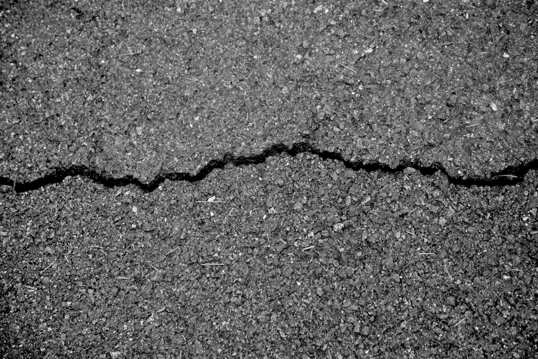 A dark crack crossing the surface of an asphalt road
