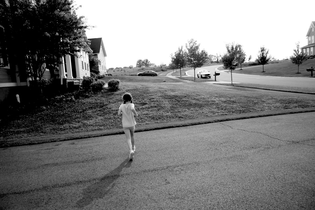 A child walking alone across a quiet suburban street