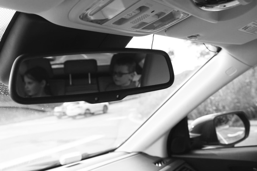 Two children reflected in a car’s rear-view mirror