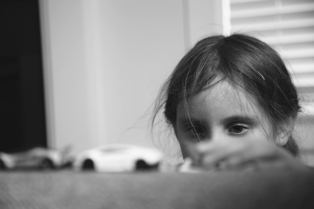 A girl’s eyes appearing above a row of toy cars